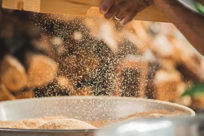 Detail shot of man's hands sifting sawdust.