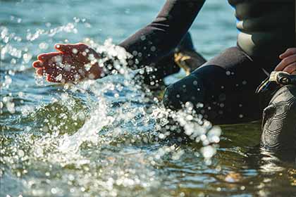 Close up of Man's hand splashing water in lake.