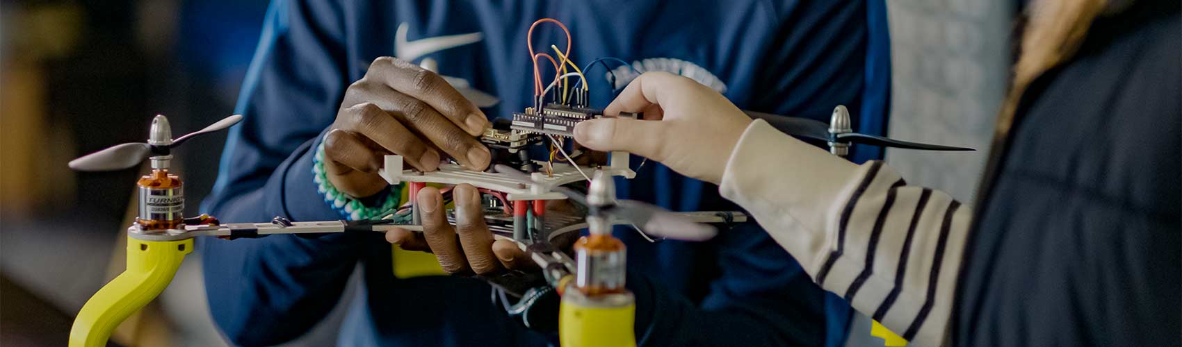 hands of two people working on drone