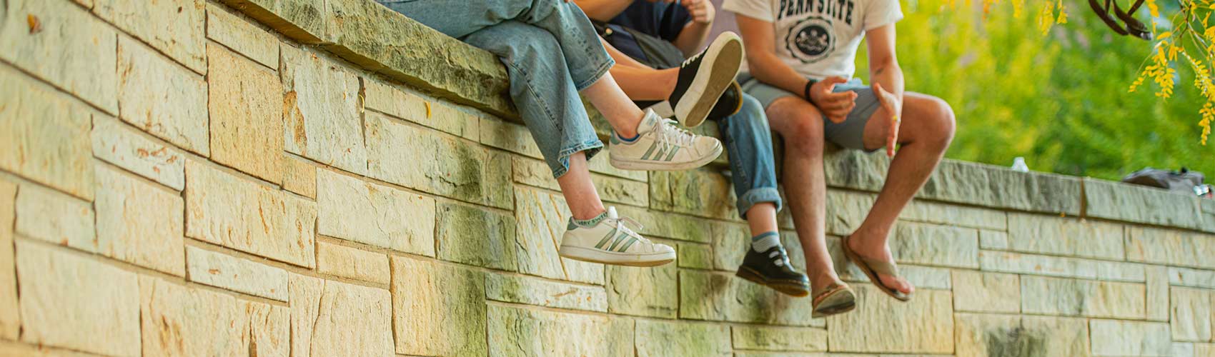 legs of students sitting on a wall